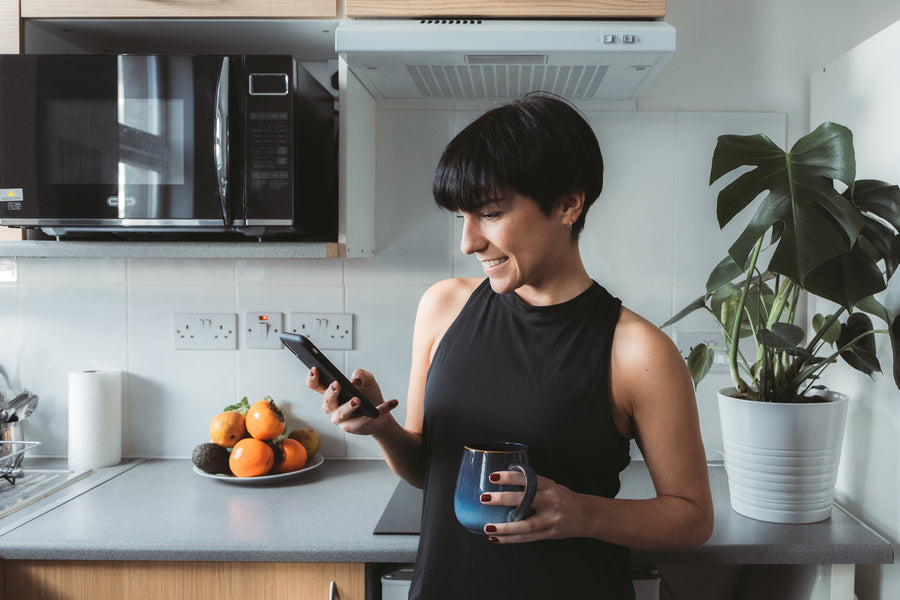 A woman at home in her kitchen, looking at her phone