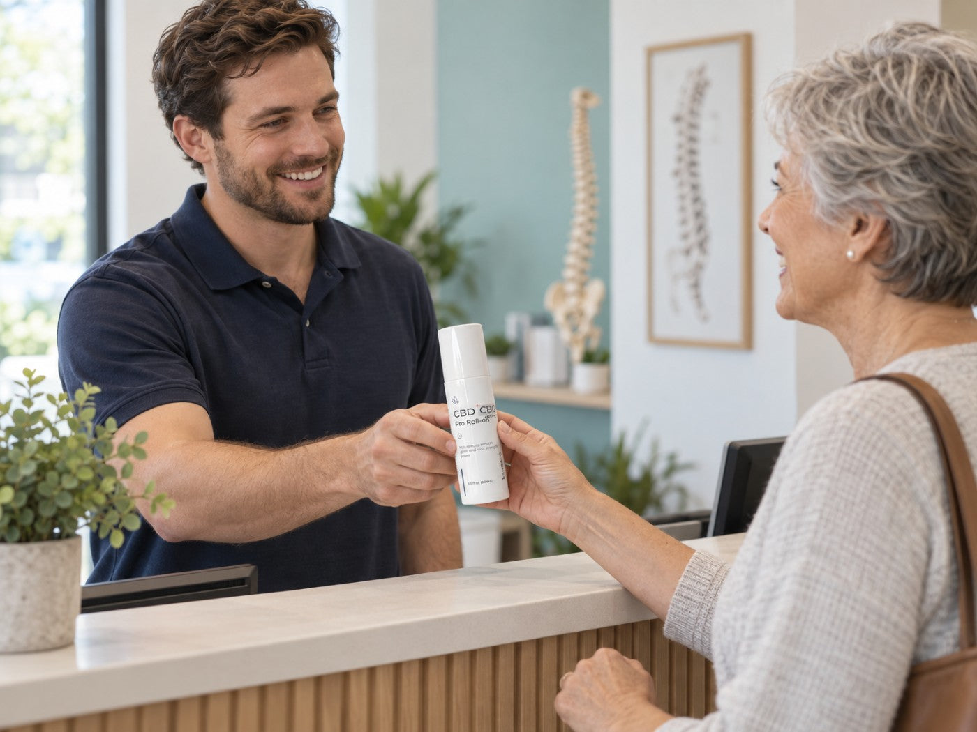 A practitioner hands a Kannaco bottle to a client across the front desk